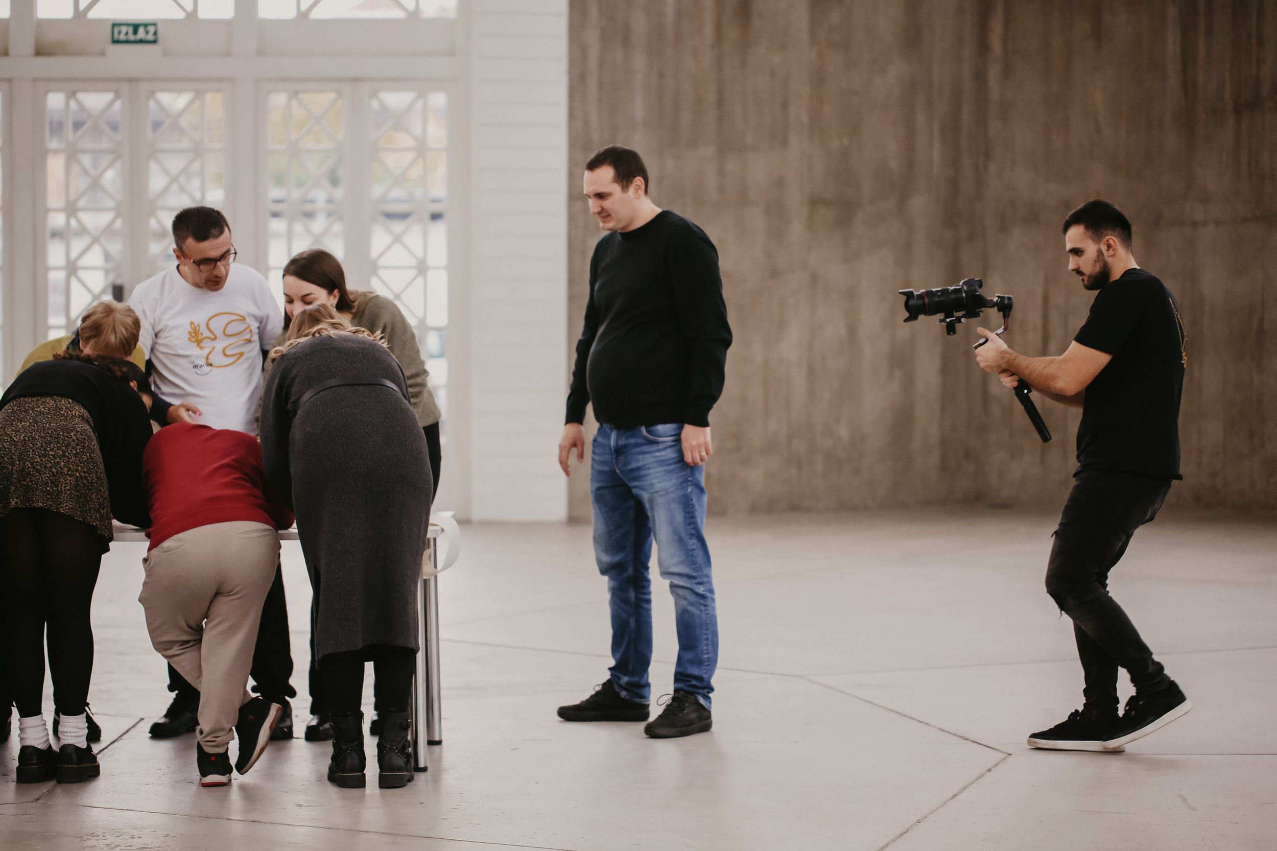 People gathered in small groups while photographers capture moments in a bright indoor space.