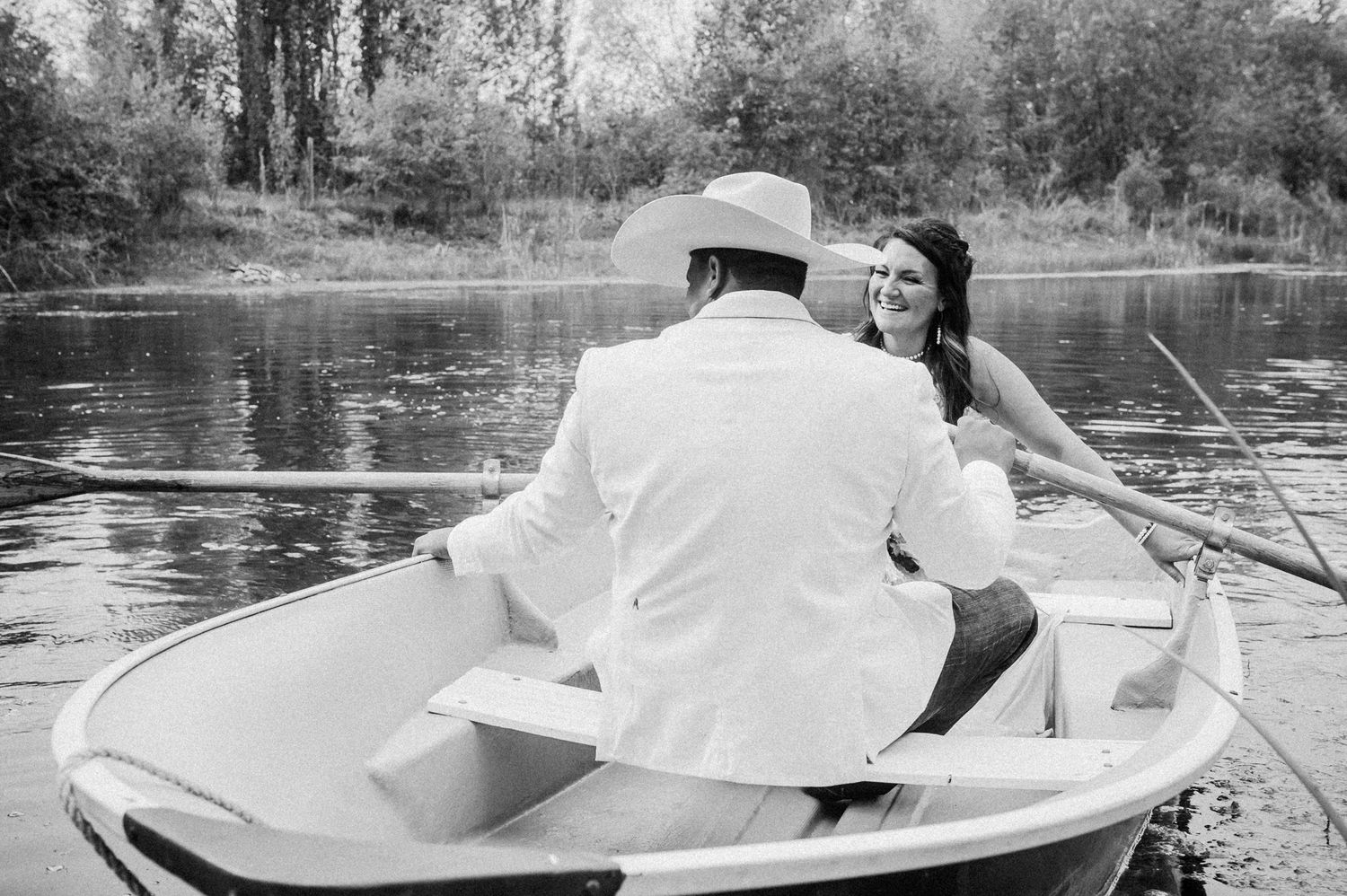 A couple enjoying a peaceful moment in a rowboat on a tranquil lake.