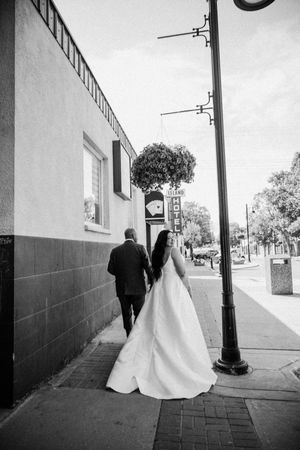 A black and white photo series showing a couple walking along a sidewalk with a bride in a flowing white dress.
