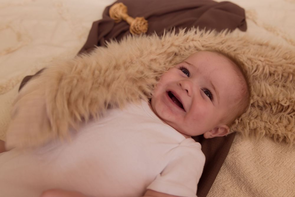 baby smiling on brown and tan blankets