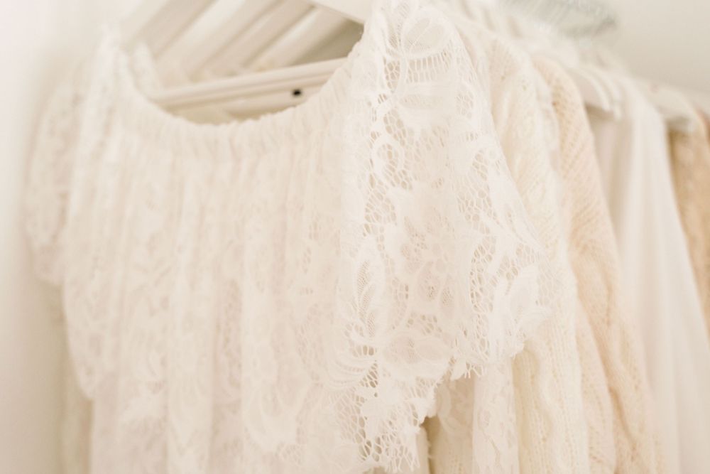 Delicate cream lace dress hanging on a rack, showcasing intricate floral lace detailing.