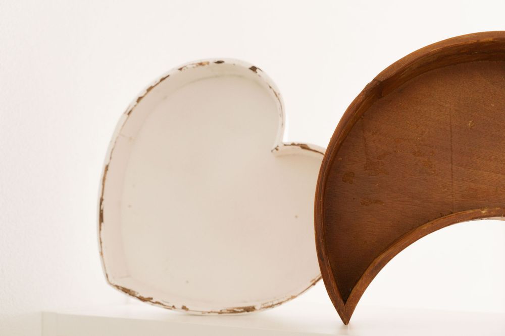 Rustic white heart-shaped wooden box with brown interior lid on white surface.