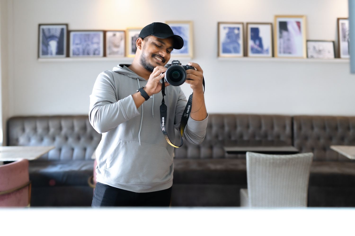 Photographer wearing gray sweater takes photo with professional camera in indoor setting.