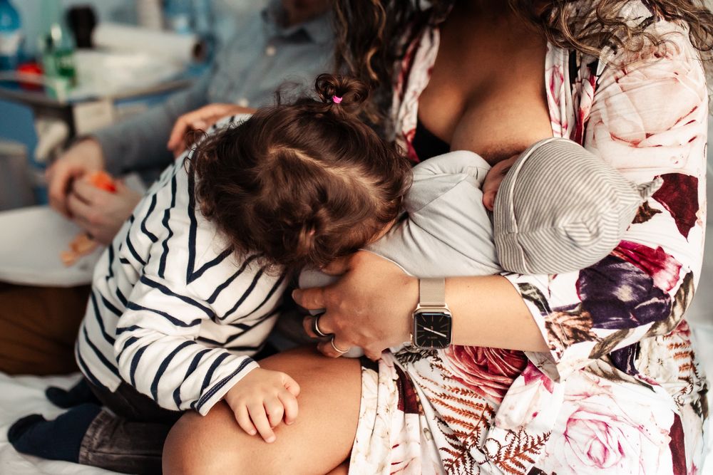 Family bonding with newborn baby in floral dress and striped clothing.