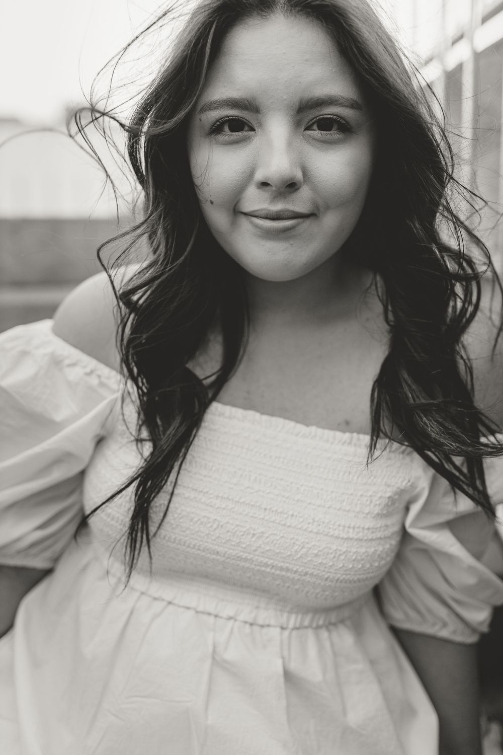 Portrait of person in white off-shoulder dress with long dark hair.