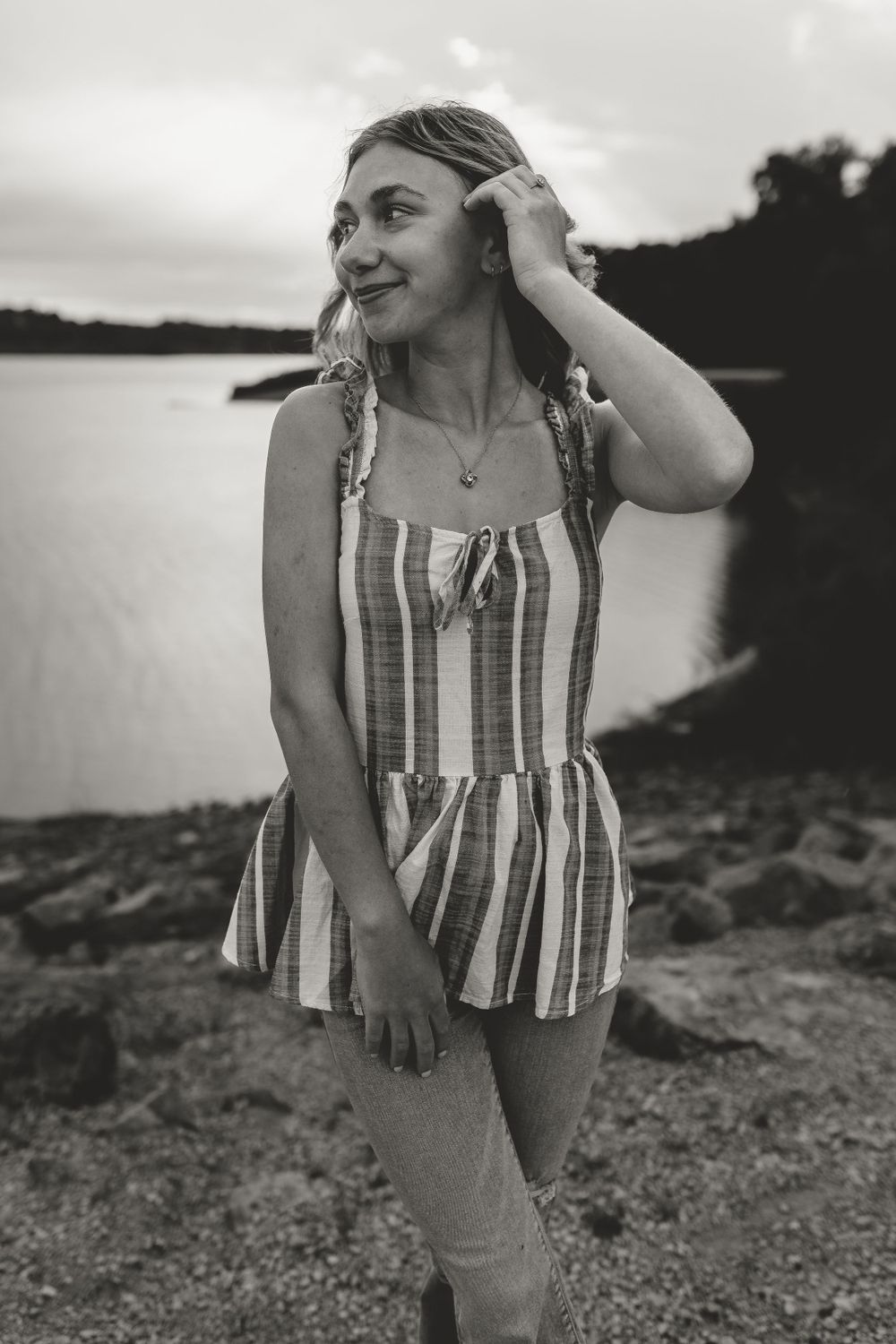 Black and white portrait of someone in a striped sundress by a lakeside.