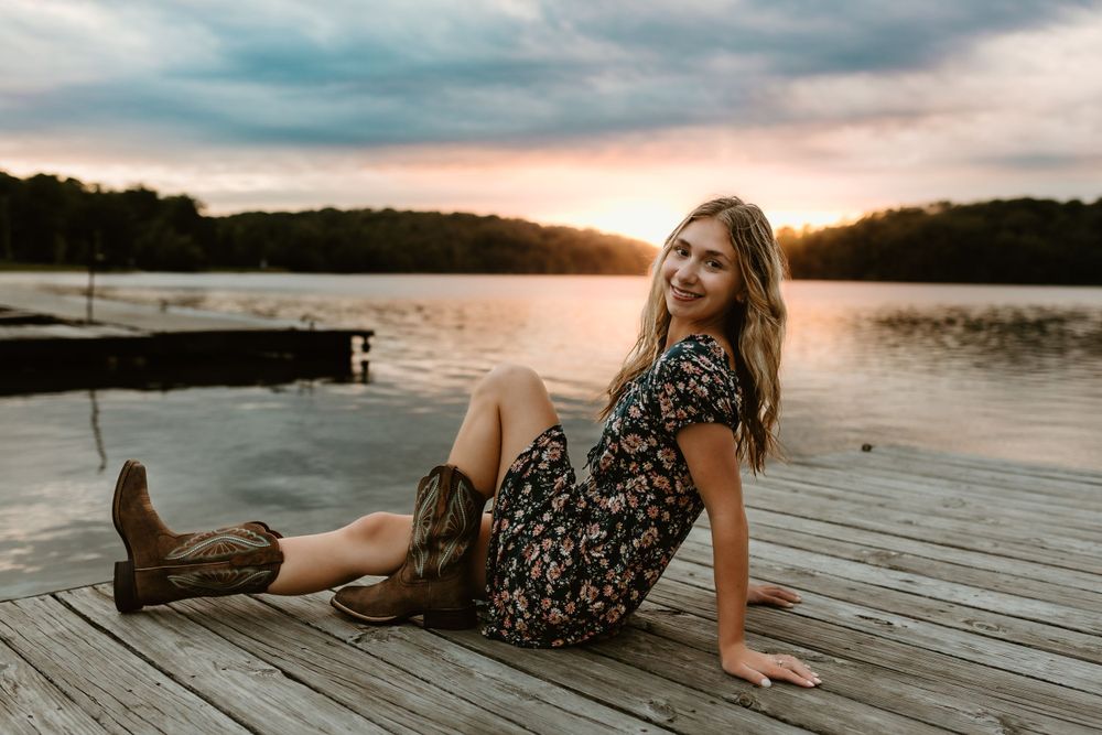 Someone relaxing on wooden dock during golden hour sunset.