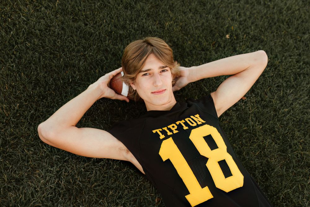 Person lying on grass wearing black and yellow sports jersey number 18.