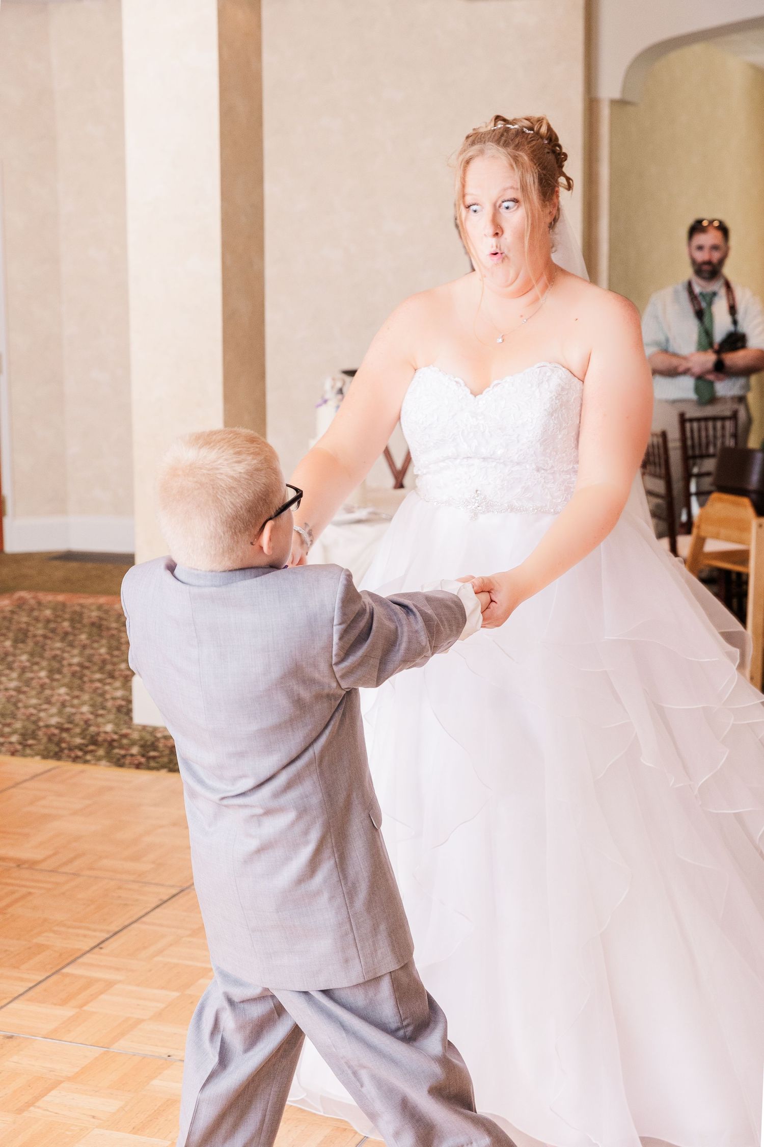Sweet dancing moment captured at wedding reception on elegant tile floor.