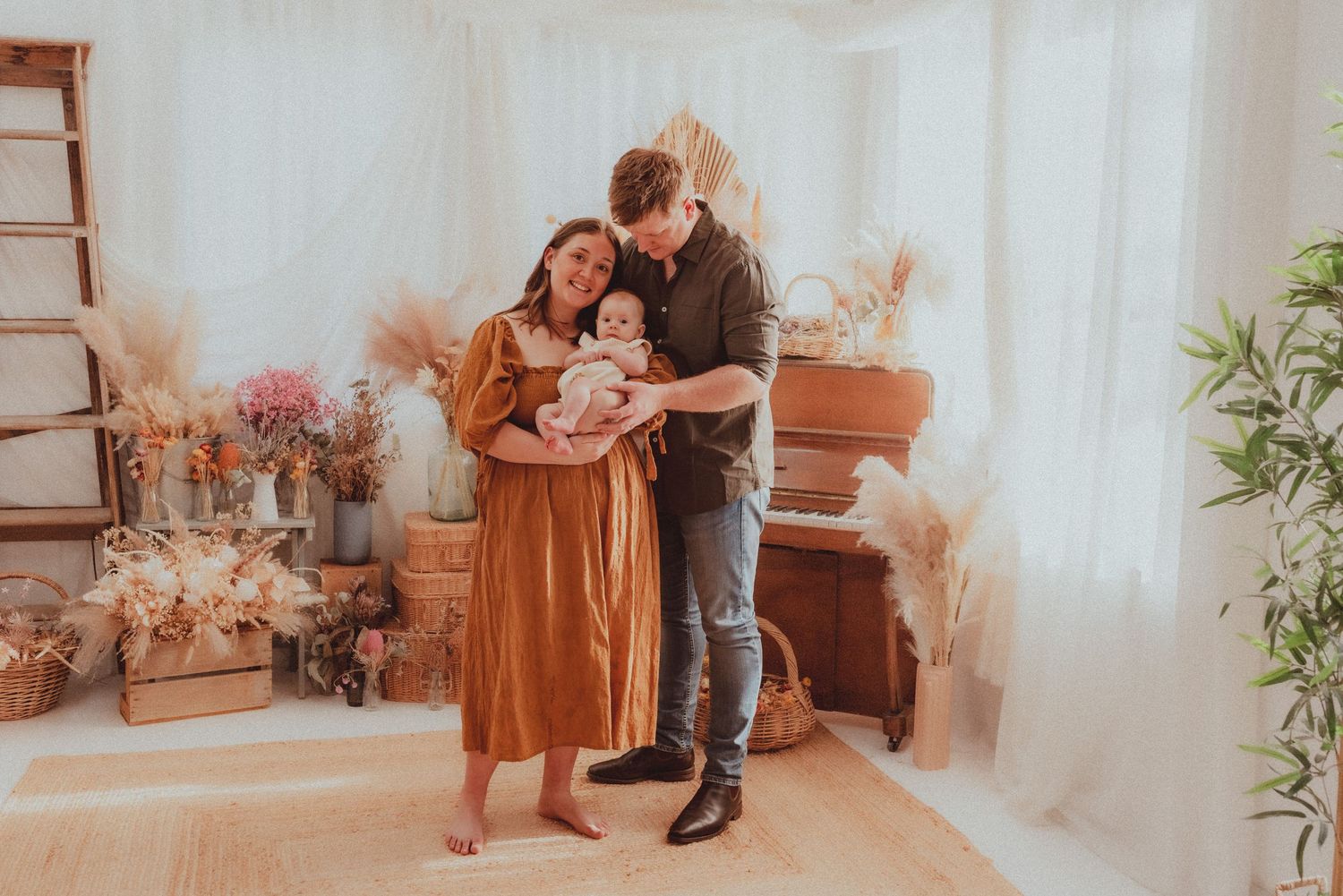 Family moment captured in bright indoor setting with piano and dried floral decorations.