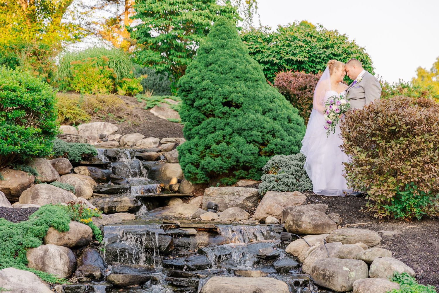A beautiful rock waterfall feature cascades down landscaped garden steps.