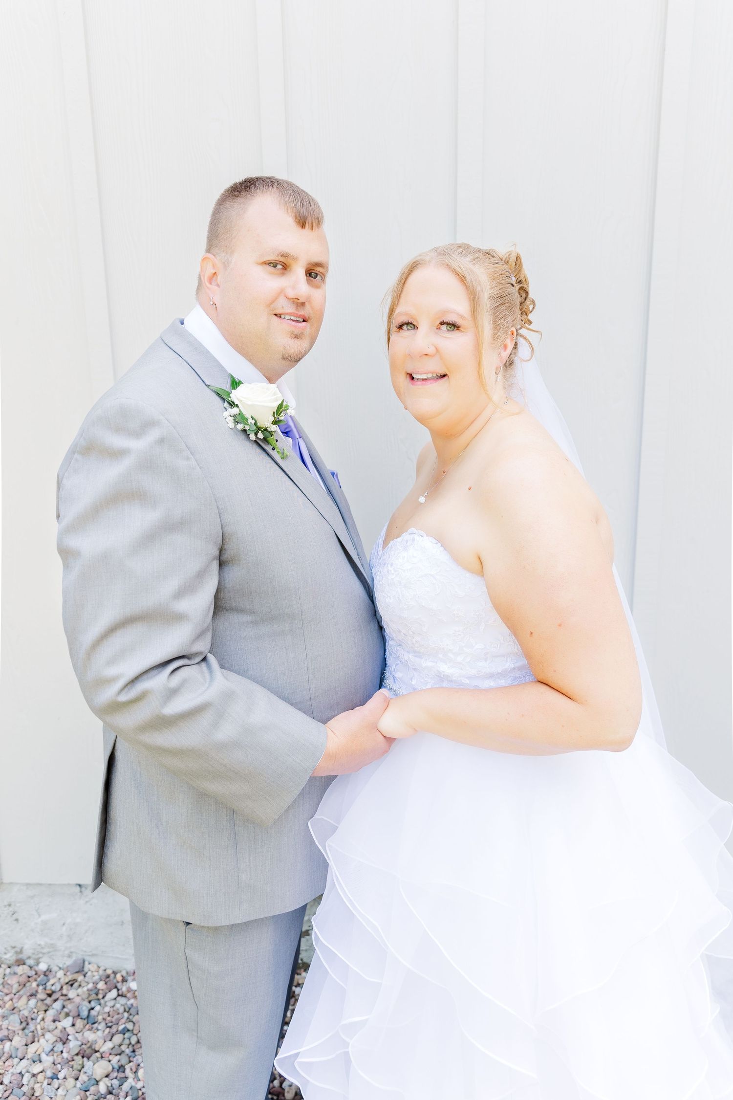 A wedding portrait of a couple in traditional attire against a light background.