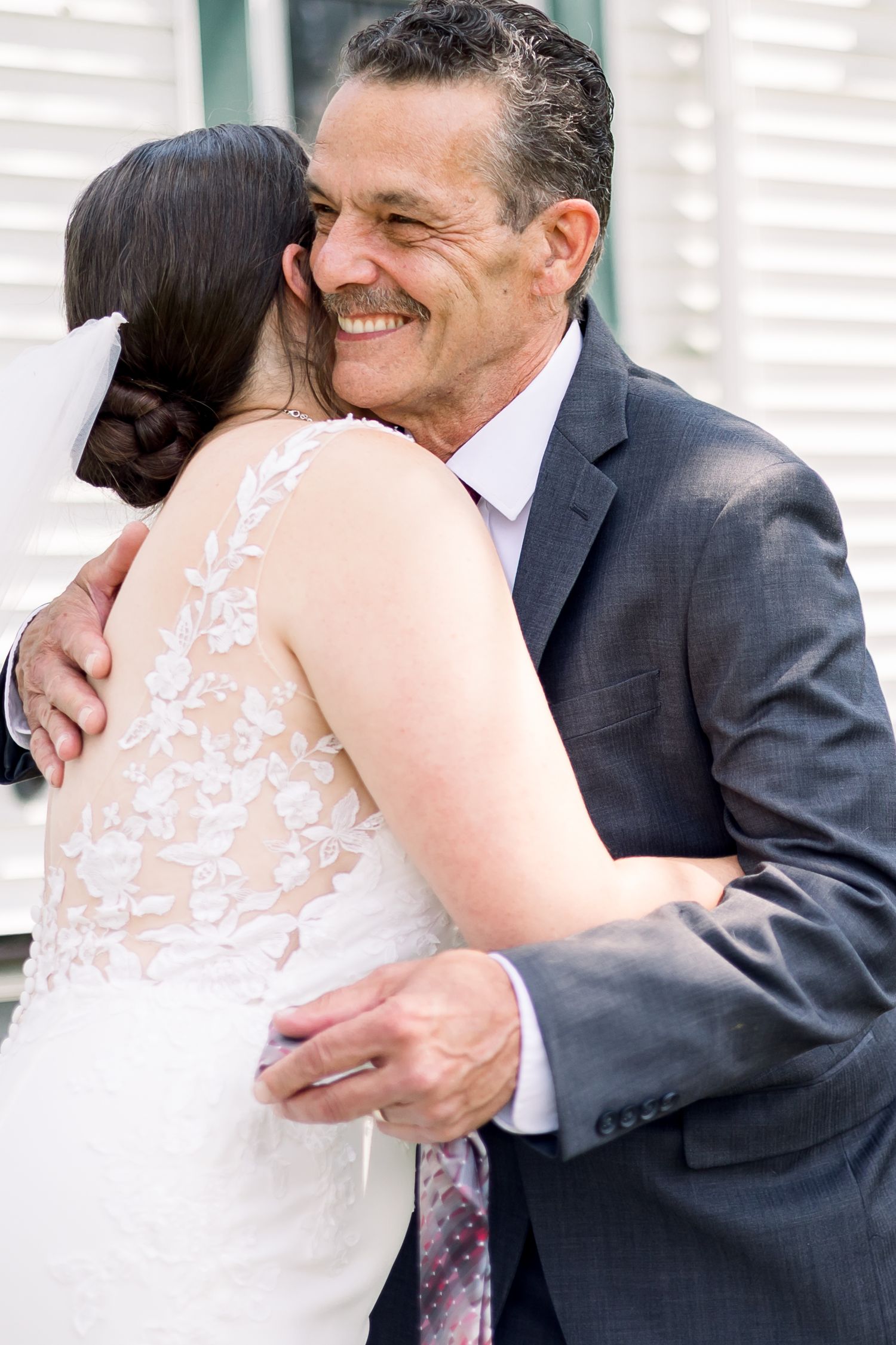 Emotional wedding day embrace captured in natural light with lace dress details.