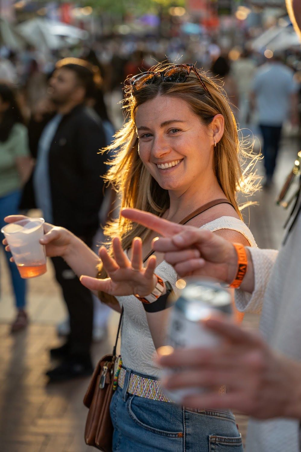 Girl with blonde hair, back lit by setting sun, reaches towards the photographer during a festival celebration in downtown Charlottesville.