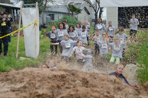 Runners participating in a muddy obstacle course race through challenging terrain.