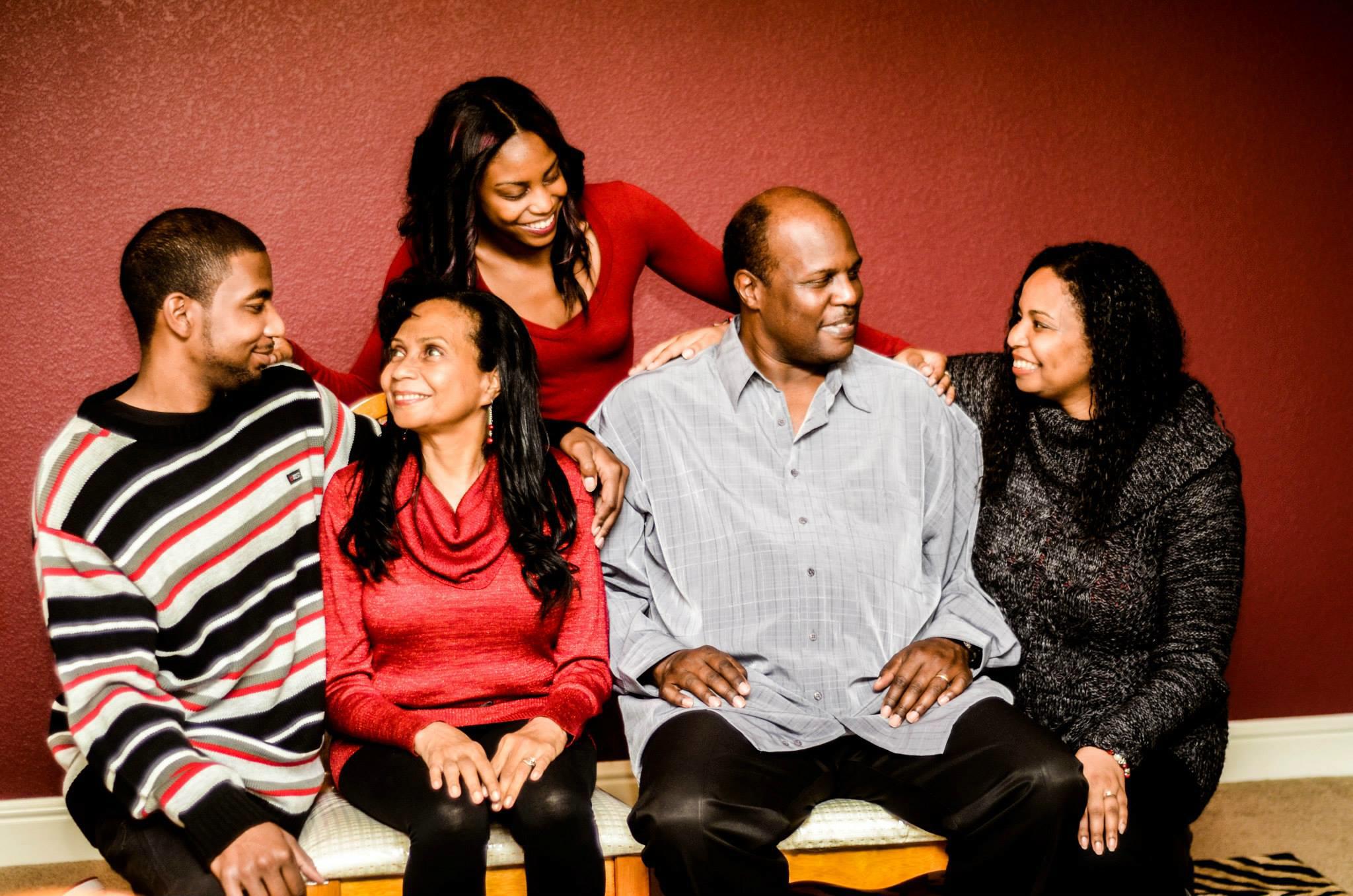 A group lounges casually on a couch in a warm-toned room wearing coordinated outfits.