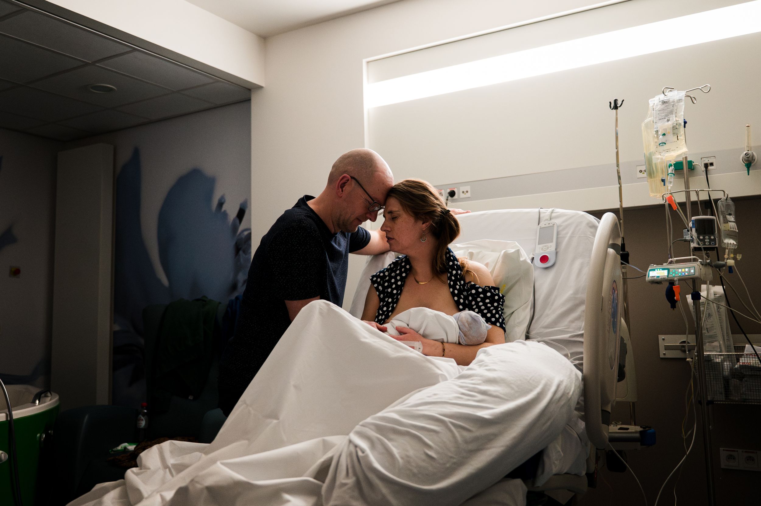 Black and white intimate moment with newborn wrapped in hospital blanket.