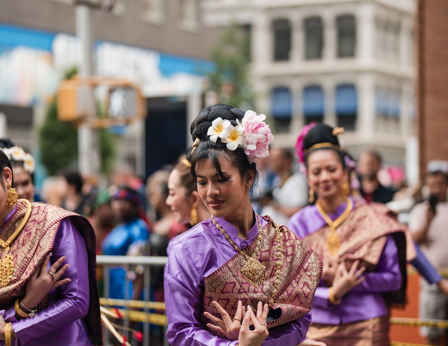 Women dressed in traditional Thai clothing performing a cultural dance in a lively outdoor setting.
