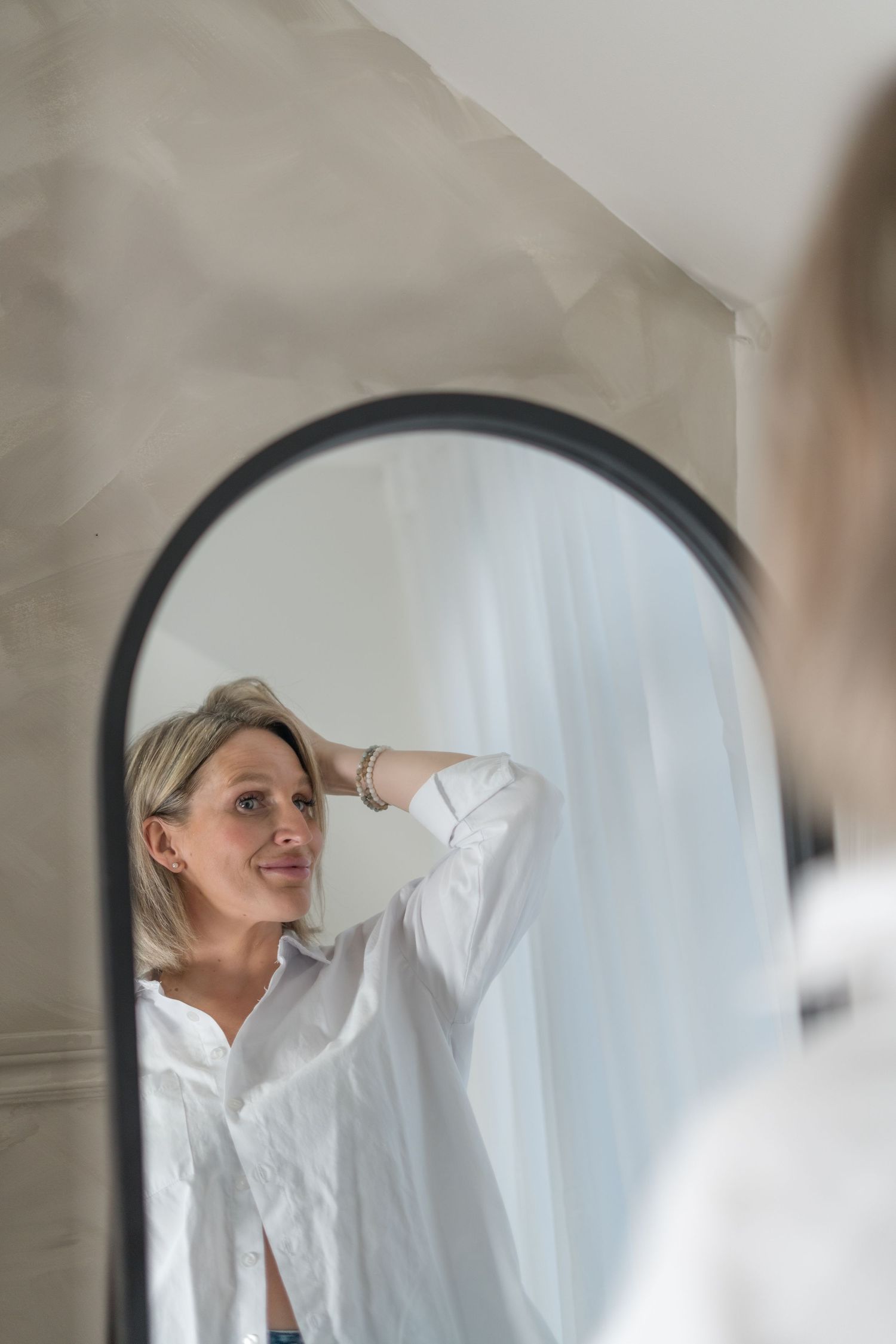 Reflection in a circular mirror shows a person in white shirt against neutral background.