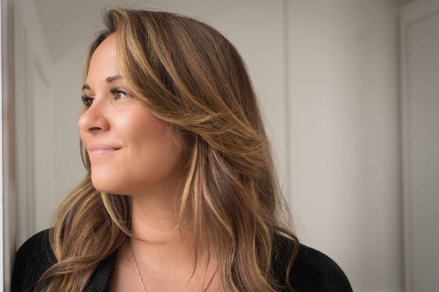 Soft profile portrait with wavy hair against neutral background.