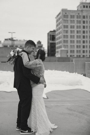 A romantic rooftop wedding moment in black and white with city buildings in the background.