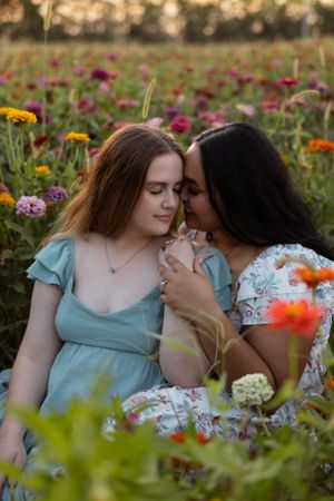 Intimate moment between friends sitting among colorful wildflowers at sunset.