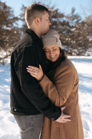Couple embracing outdoors in snowy winter scene wearing warm coats.