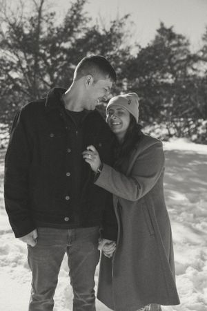 Black and white photo of couple sharing tender moment in snowy setting.