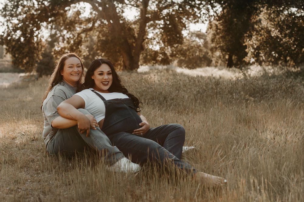 Two people share joyful moments while lounging in a sunlit field with golden grass.