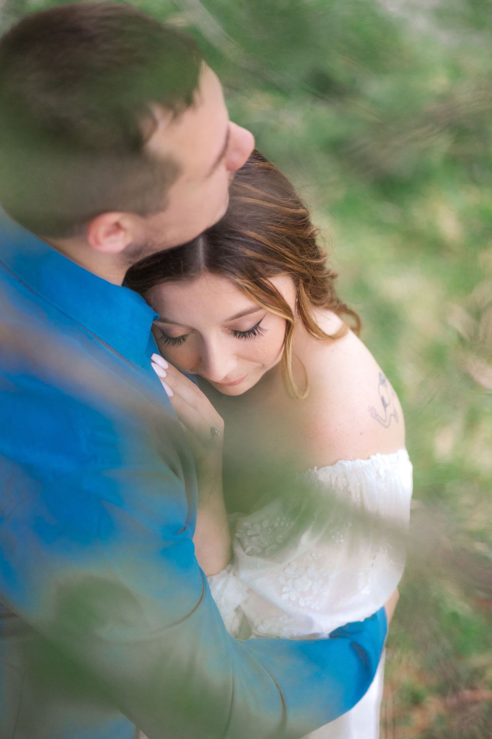 Intimate soft-focus portrait of couple embracing outdoors during romantic photoshoot.