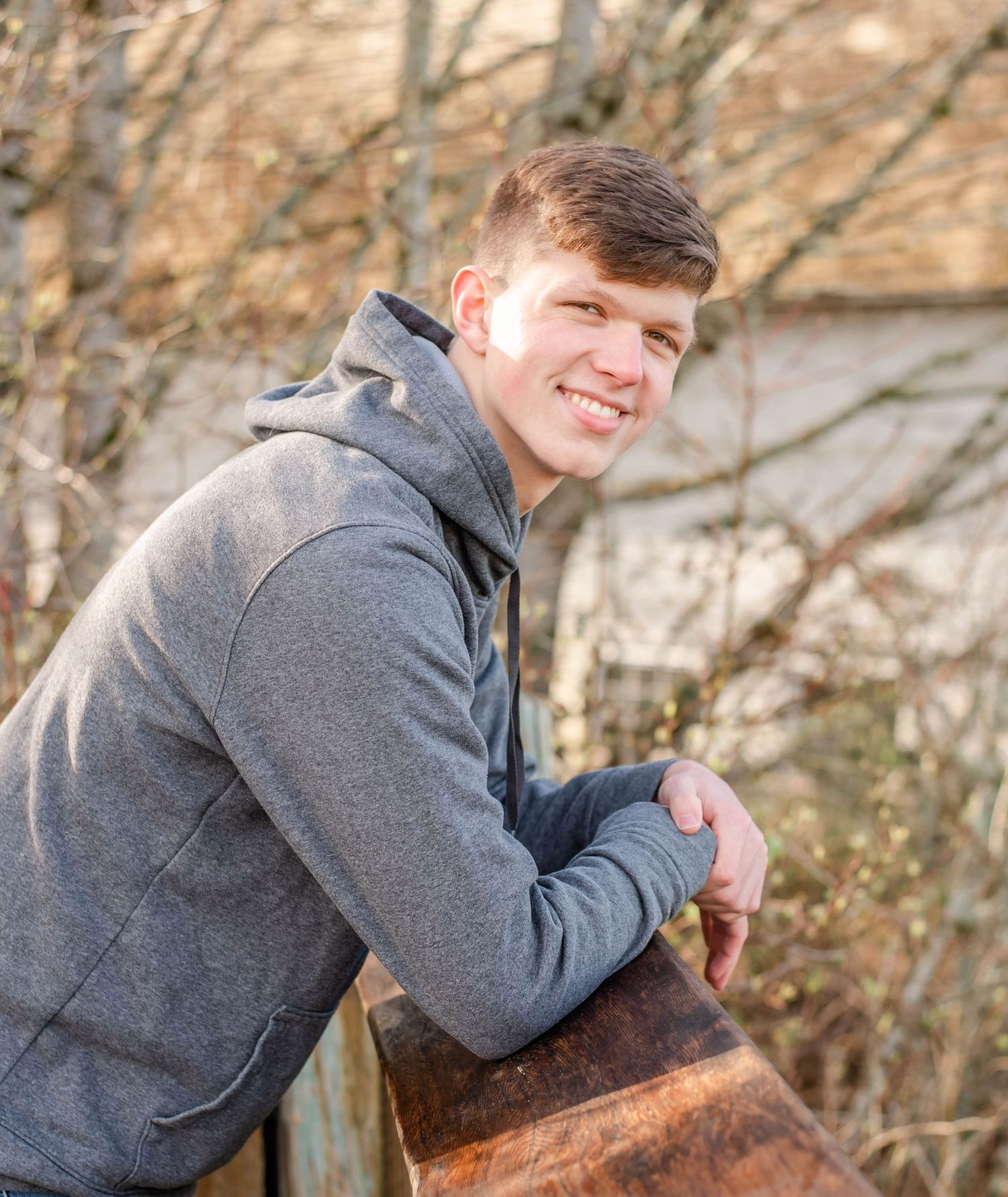 Casual outdoor portrait session against a rustic wooden backdrop.