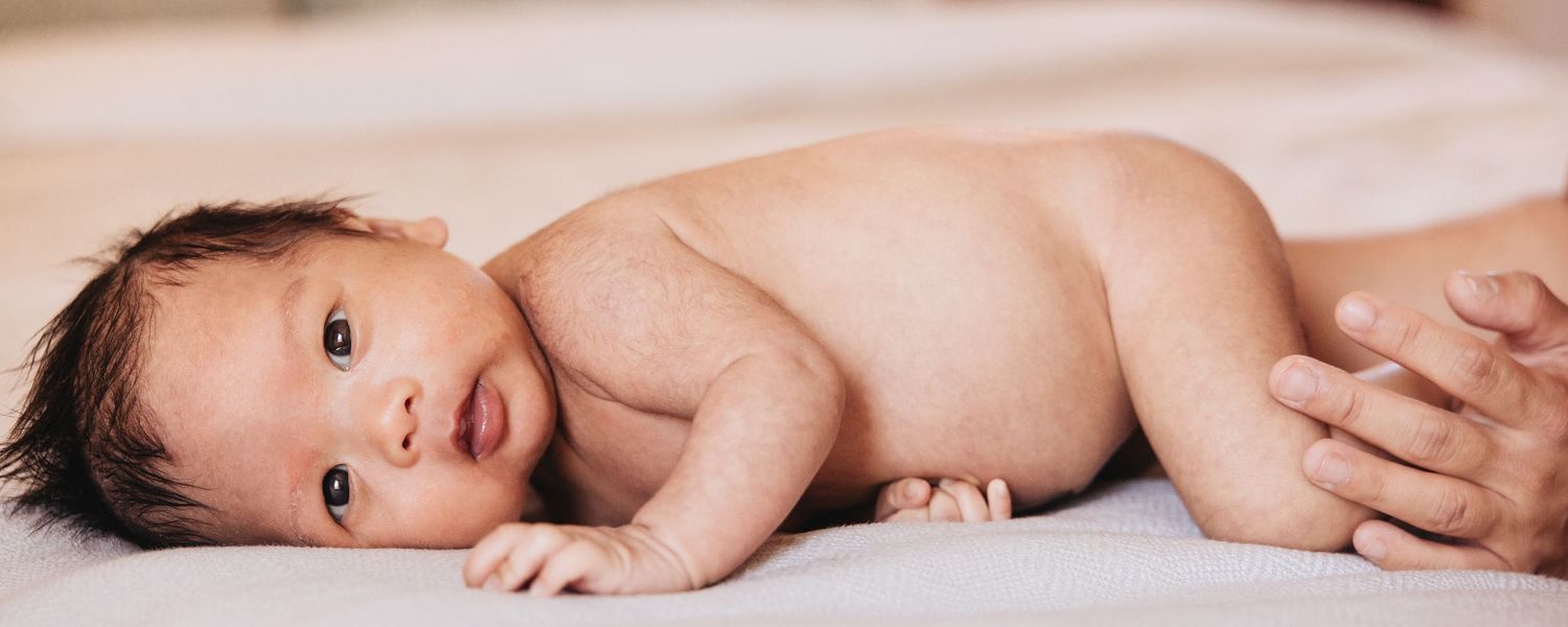 Intimate newborn photography session with parents in bright bedroom setting.