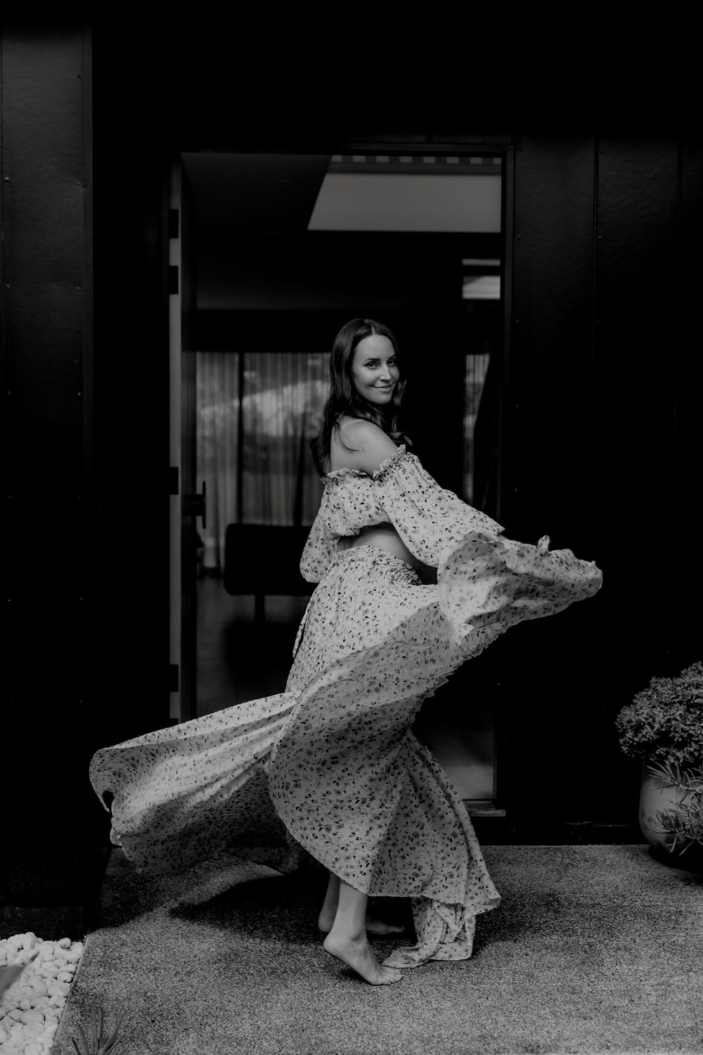 Dynamic black and white photo of person twirling in patterned dress.