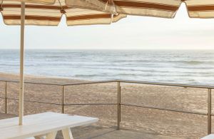 Beachfront dining area with white umbrellas overlooking ocean waves.