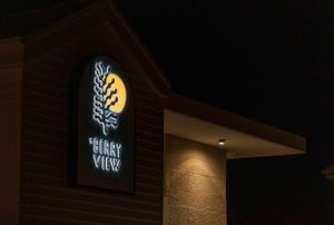 Illuminated The Berry View hotel sign with leaf design glowing at night.