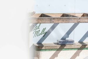 Stylish green lettering detail on a white architectural element with shadows.