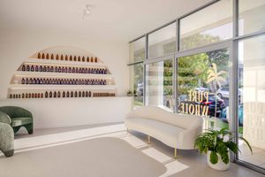 Bright white interior of a modern nail salon with shelves of polish bottles and large windows letting in natural light.