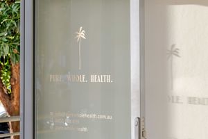 A frosted glass door with a palm tree logo and text reading 'Pride Wealth' casts shadows on a white wall.