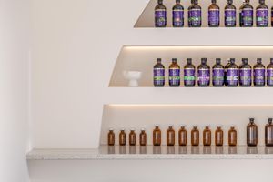 Rows of amber glass bottles line minimalist white shelves in a modern retail display.