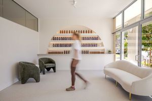 Modern nail salon interior with white walls, floating shelves displaying colorful nail polish bottles in neat rows.