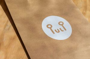 Close-up detail of a brown paper bag with circular white Pulp logo branding.