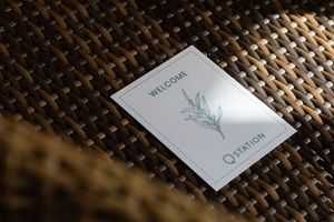 A white welcome card with floral design sits on a woven textured surface.