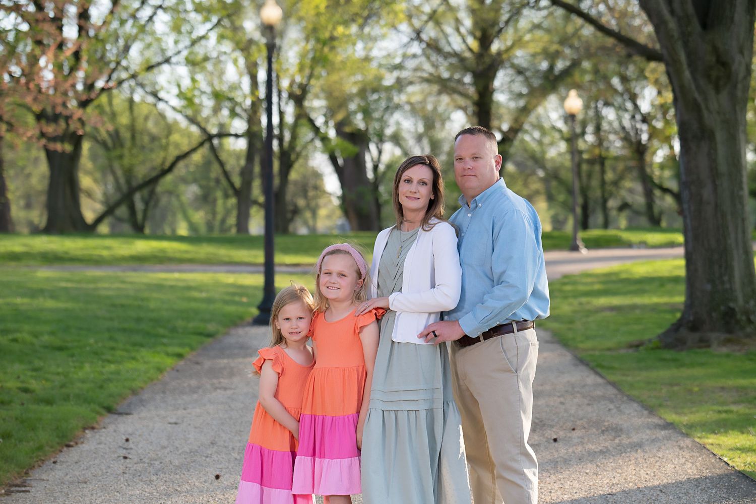 Family walking together in a park in matching pink outfits on a sunny spring day.