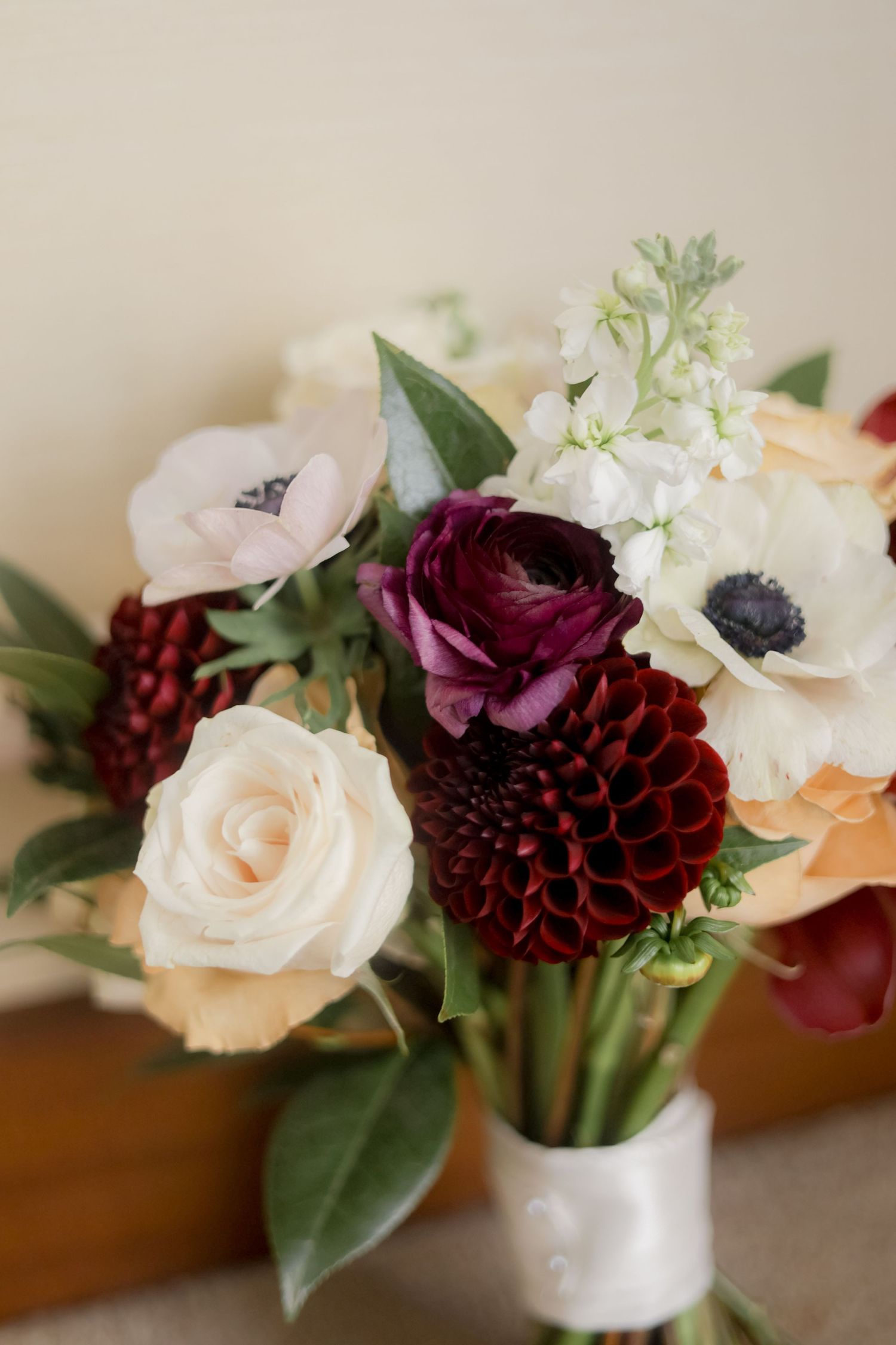 Close-up of wedding bouquet featuring burgundy dahlias, white roses, and anemones.