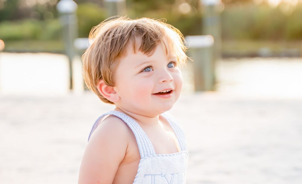 A child wearing a striped dress plays in a sunny garden on a warm summer day.