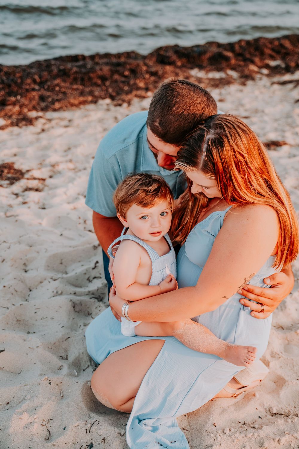 A tender family moment captured in a series of beach photos showing parents and child embracing on sandy shoreline.