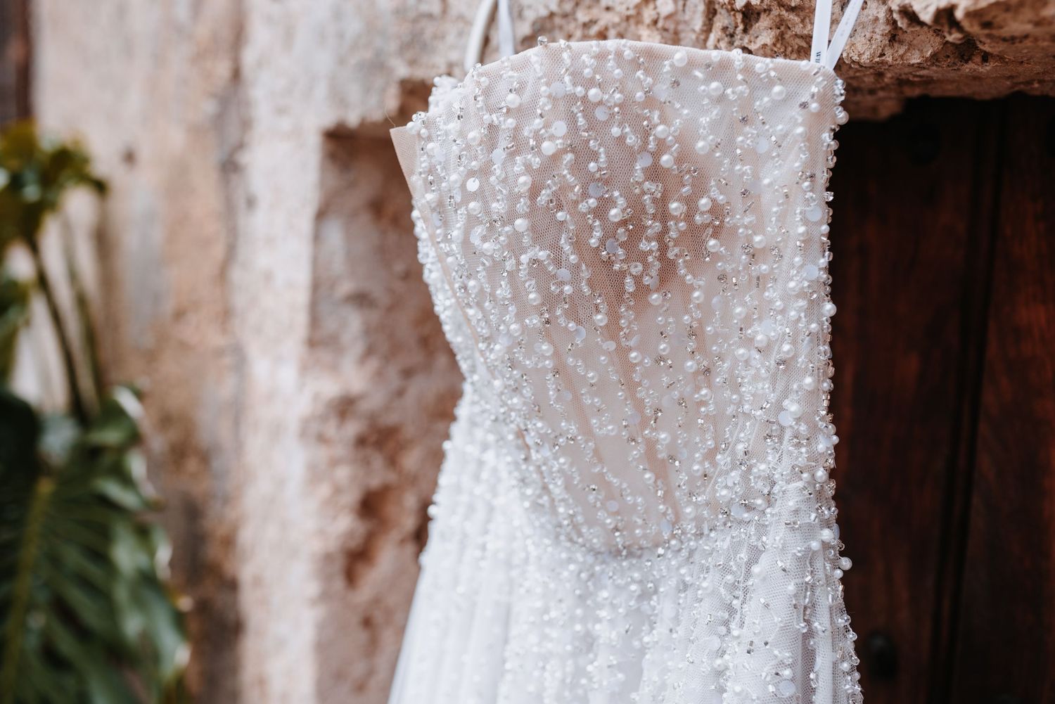 Ein weißes Brautkleid mit Perlenstickerei, besticht durch aufwendige Verzierungen aus Perlen und Kristallen, die im Detail schimmern.
