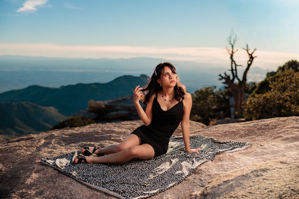 Senior girl in a black dress sitting on a blanket on Mt. Lemmon overlooking vistas
