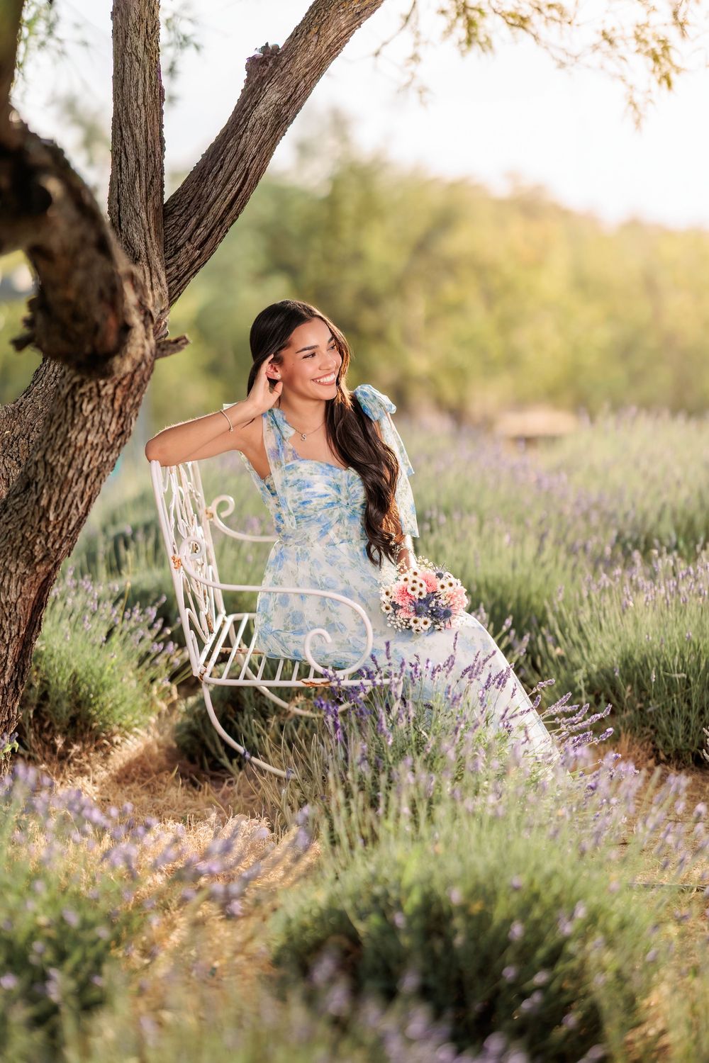 senior girl in a lavender field with a long flowing dress holding flowers