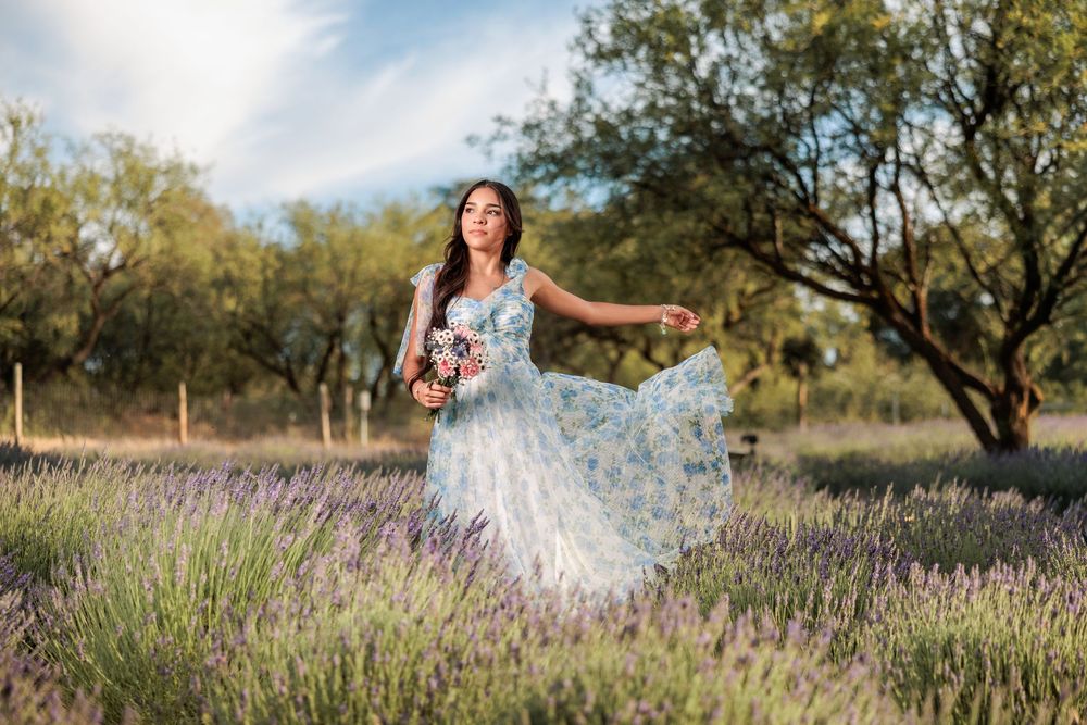 senior girl in a lavender field with a long flowing dress holding flowers